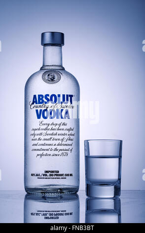Bottle and a glass of vodka Absolut toned in blue Stock Photo