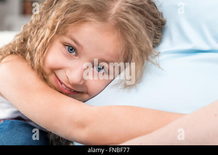 Happy little girl hugging pregnant mother Stock Photo