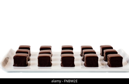 Front view of rows of dark chocolate truffles on a white square plate. Stock Photo