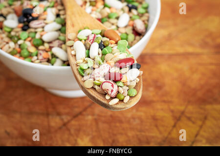 Mixed dried legumes and cereals in wooden spoon on wooden background. Copy space Stock Photo