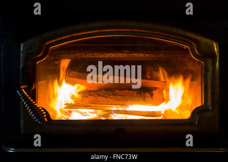 Burning wood in a fireplace in the winter with orange flames. Stock Photo