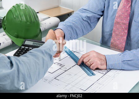 Detail of two designers who work in their studio with a project work plan agree with a handshake. Stock Photo