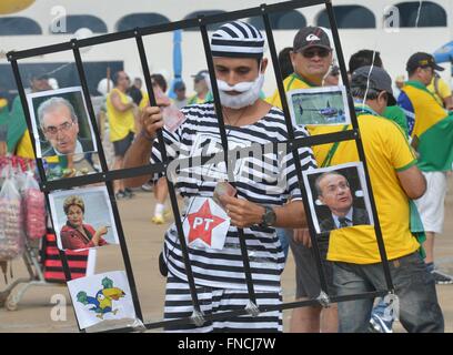 Brasilia, Brazil. 13th Mar, 2016. A protester wearing prisoner stripes joins thousands gathered outside the government district in the capital to demand the resignation of Brazilian President Dilma Rousseff March 13, 2016 in Brasilia, Brazil. Rousseff rejected calls for her resignation amidst a political storm deepened by a massive corruption scandal. Stock Photo