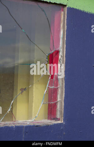 Cracked window in a colorfully painted rustic building at a carnival. Stock Photo
