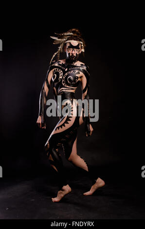 girl painted with black paint in the image of warrior women on a black background Stock Photo