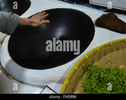 (160315) -- SUZHOU, March 15, 2016 (Xinhua) -- Yan Jielong feels the temperature of pot before baking Biluochun tea in Dongshan Town, Suzhou City of east China's Jiangsu Province, March 14, 2016. Yan Jielong, 53 years old, inheritor of ancient making technique of Chinese tea Biluochun, has learnt the skill since he was 16 years old. Requiring high standard of making technique, Biluochun tea is the speciality of Dongshan Town, where the people who know the ancient making technique are mostly in their 50s. Yan and other inheritors have taken video of their method and hope they may someday open a Stock Photo