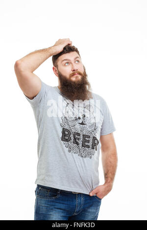 Pensive handsome bearded man scratching his head and thinking over white background Stock Photo