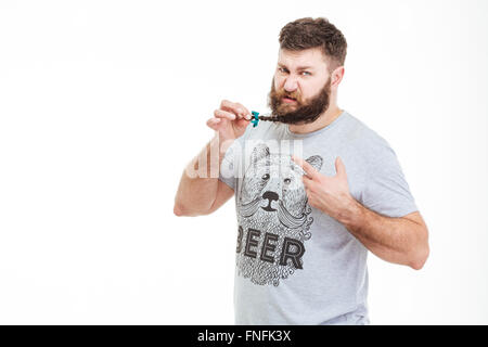 Brutal bearded man standing and showing small braid on his beard over white background Stock Photo