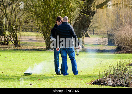 Lund, Sweden - March 12, 2016: Two males are having a conversation in the park. Beside them is a disposable grill on the lawn. R Stock Photo