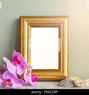 Image of a gilded frame mockup scene, with orchids and sea shells. Stock Photo