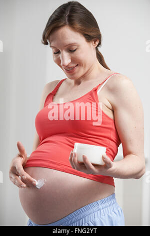 Pregnant Woman Moisturizing Belly Stock Photo