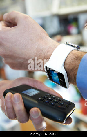 Man Using Contactless Payment App On Smart Watch In Store Stock Photo