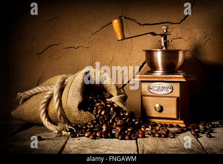 Coffee grains and mill in cellar with clay wall Stock Photo