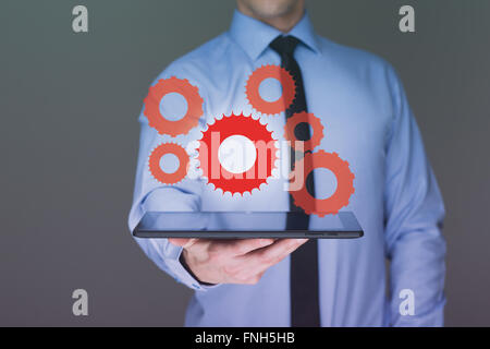 businessman hand touch  gear to success as concept. Business man using tablet PC. Stock Photo