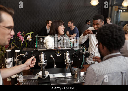 Woman laughing with African friend at counter of coffee shop Stock Photo