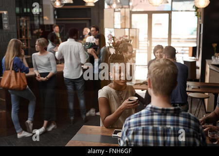 Busy coffee shop with African woman and friends talking Stock Photo