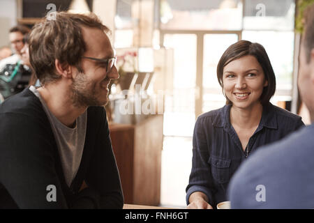 Smiling woman at a table with friends in modern cafe Stock Photo