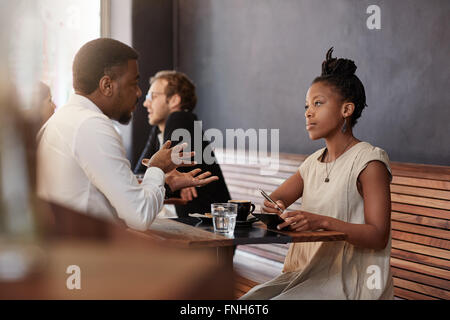 African woman having meeting with a man in busy cafe