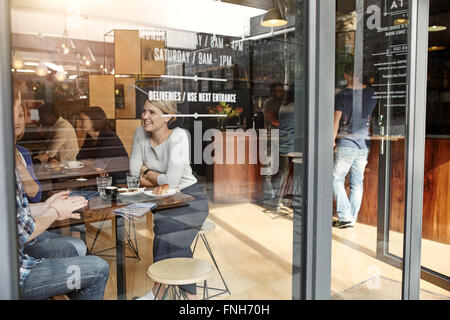 Woman with friends at a cafe seen through window Stock Photo