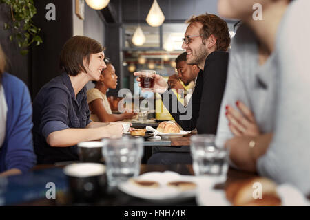 Busy cafe with a young couple smiling at each other Stock Photo