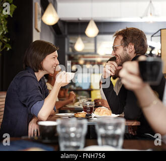 Smiling couple having coffee together in a busy cafe Stock Photo