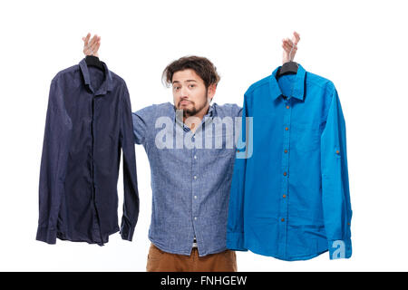 Man trying to choose between two shirts over white background Stock Photo