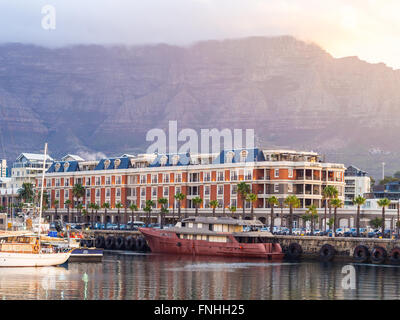 Waterfront in Cape Town, South Africa, overlooked by Table Mountain at sunset.