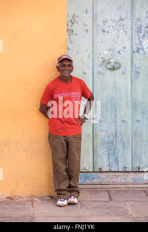 Daily life in Cuba - Cuban man stood against wall smiling at Trinidad, Cuba, West Indies, Caribbean, Central America in March Stock Photo