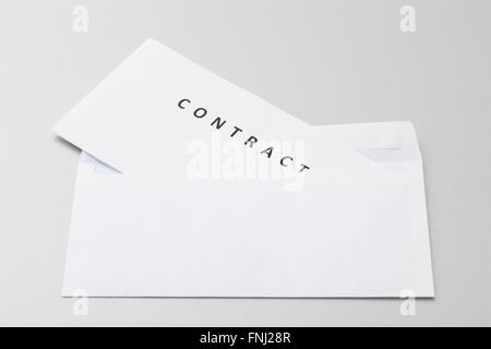 Folded white sheets with contract put in blank white envelope, ready for sending by post isolated on background. Stock Photo