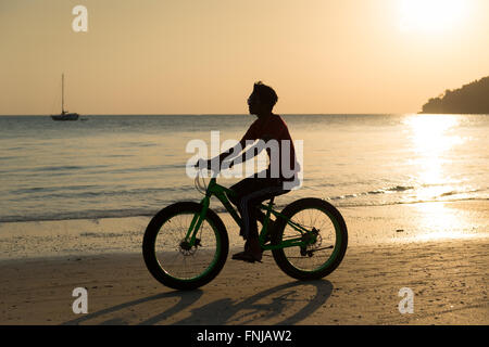 Silhouette of a man on a bike on Cenang beach, Langkawi, Malaysia at sunset Stock Photo