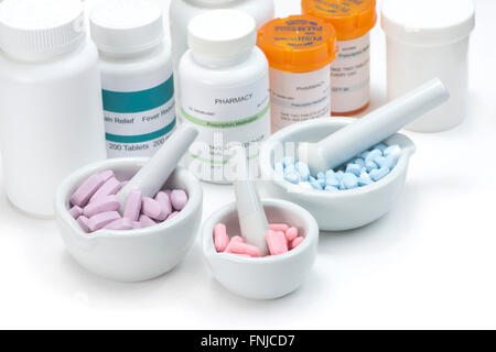 Pink, blue and purple tablets in three mortar and pestles on white background with prescription bottles. Labels are fictitious a Stock Photo