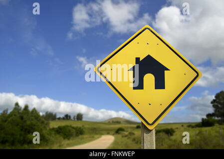 Buy your own house in the countryside, way to the home of your dreams concept. Road sign with real estate icon in nature rural e Stock Photo