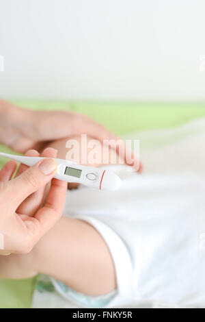 Checking baby temperature which indicates high fever on thermometer Stock Photo