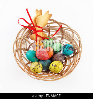 Bright Easter eggs and cookies in the form of an Easter bunny and in a wicker basket. Top view. Stock Photo