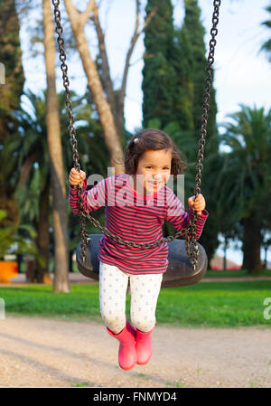 Happy three year old girl having fun on a swing Stock Photo