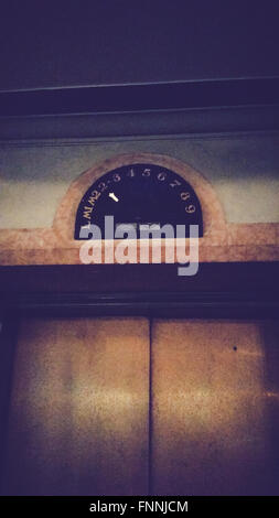 Old-fashioned elevator door with vintage floor indicator dial pointing to level 2 Stock Photo