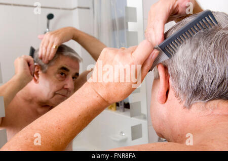 Elderly Man combing his hair and looking into mirror. Stock Photo