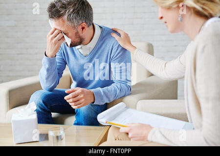 Depressed man crying while visiting his psychologist Stock Photo