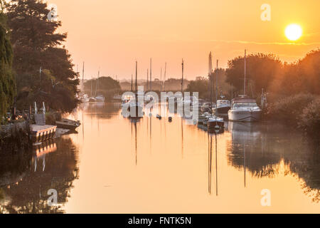 yachts moored at sunrise reflecting in water Stock Photo