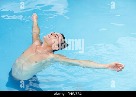 Young attractive man relaxing leaned back in ocean with blue water Stock Photo