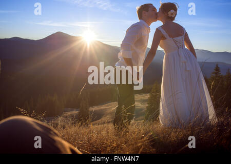 Beautiful wedding couple softly kissing. Sunset in the mountains Stock Photo