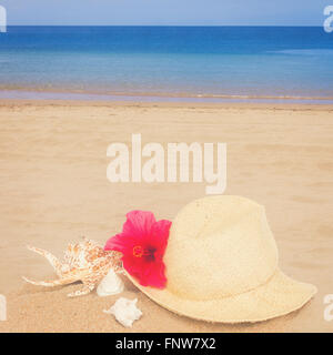 straw hat ans seashells on sand beach Stock Photo