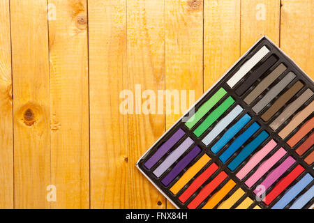 colored pastels in a box on a wooden background Stock Photo