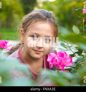 portrait of a girl in a rose bush in the park Stock Photo