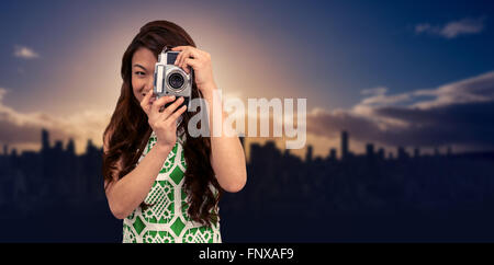 Composite image of smiling asian woman taking photograph with camera Stock Photo