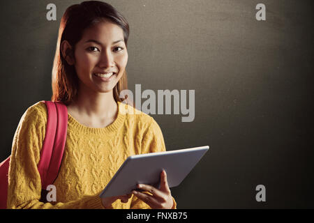 Composite image of smiling asian female student using tablet Stock Photo