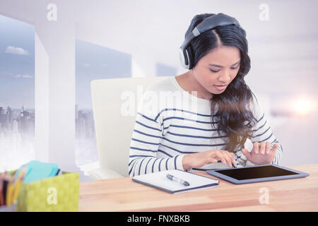 Composite image of smiling asian woman with headphones using tablet Stock Photo