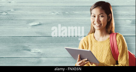 Composite image of smiling asian female student using tablet Stock Photo
