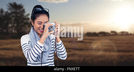 Composite image of smiling asian woman taking photograph with camera Stock Photo