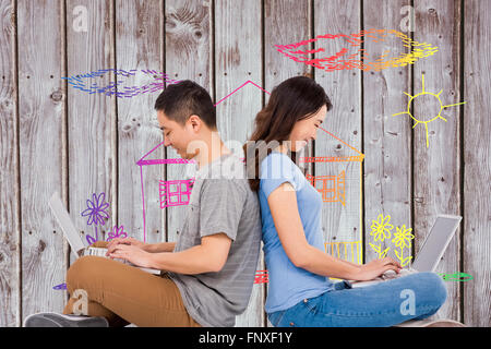 Composite image of happy young couple using laptop while sitting back to back Stock Photo